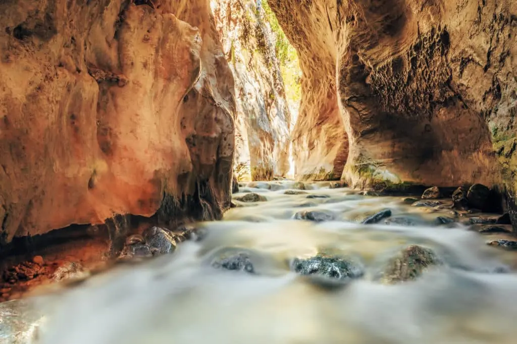 Agua corriendo entre las paredes anaranjadas de Los Cahorros, el desfiladero del Chíllar