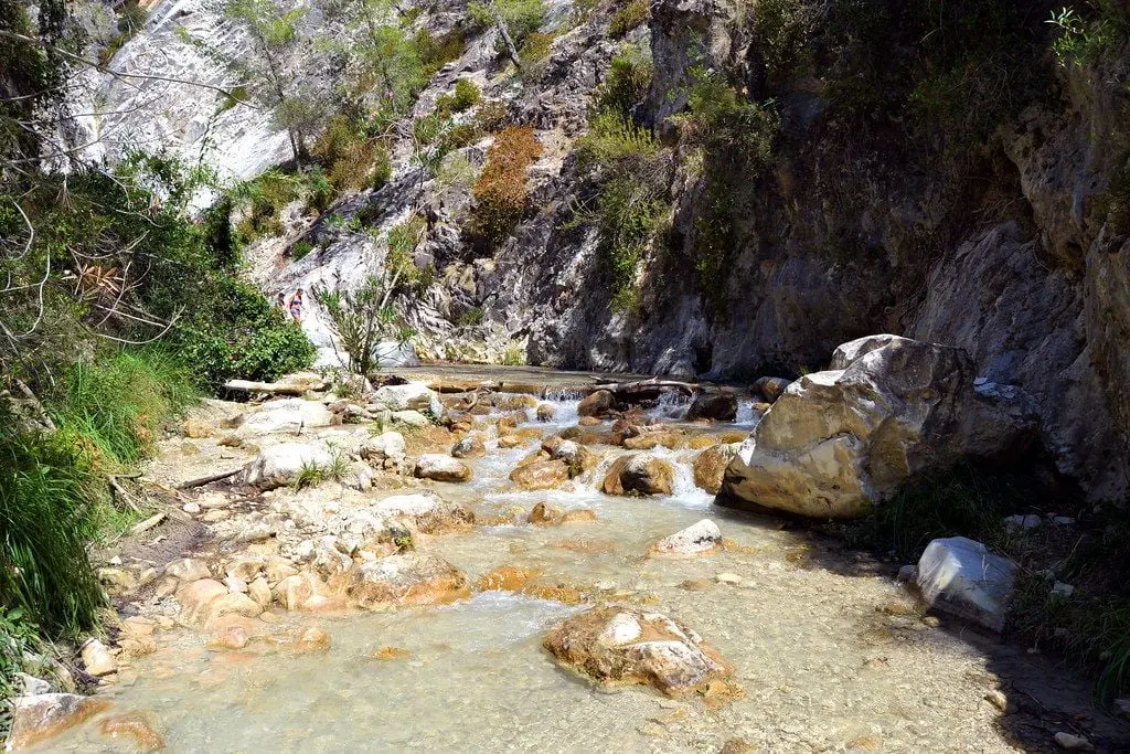 Cauce pedregoso del río Chíllar con pequeños saltos de agua bajo la ladera rocosa