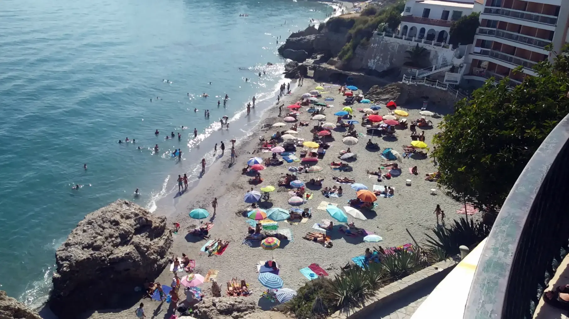 La Caletilla llena de sombrillas en verano, vista desde la barandilla del paseo
