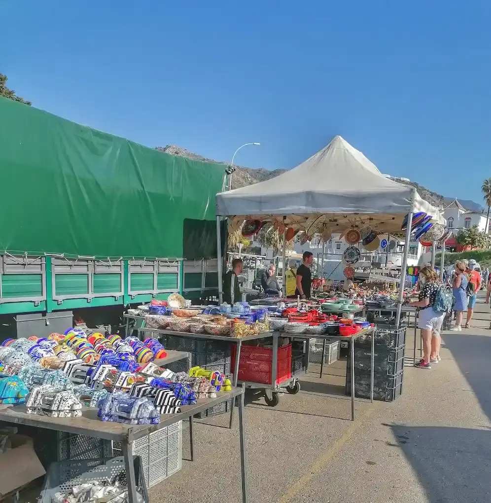 Puesto de cerámica pintada y objetos decorativos bajo una carpa blanca en el rastro de Nerja