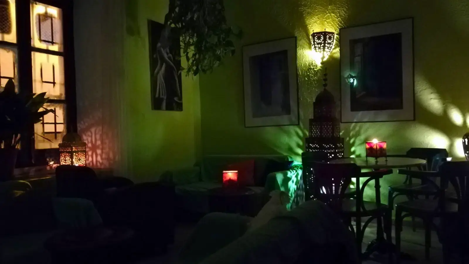Salón en penumbra con farolillos árabes, velas y luz verde en las paredes