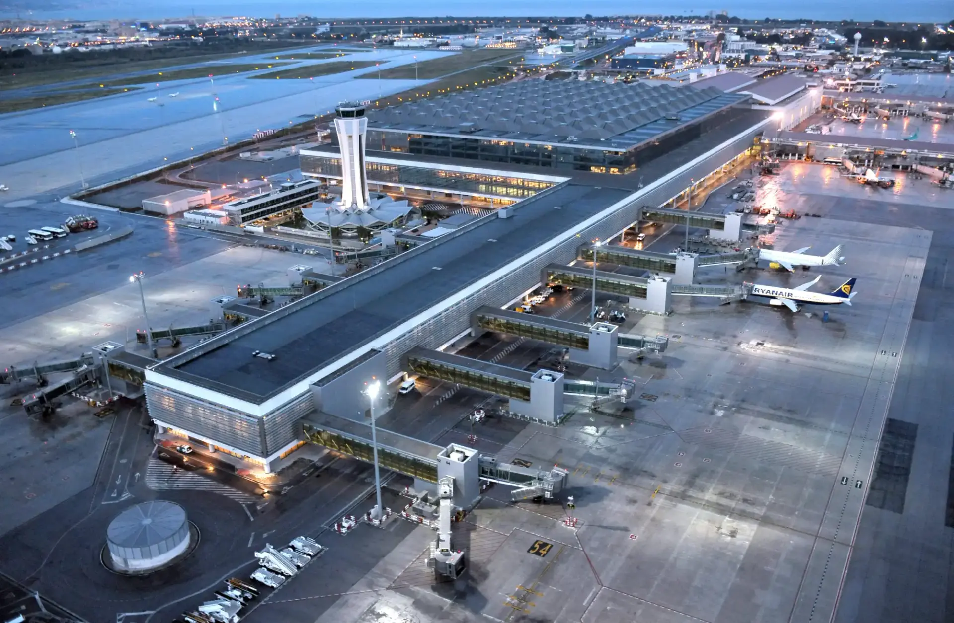 Vista aérea de la terminal del aeropuerto de Málaga con la torre de control y aviones al anochecer