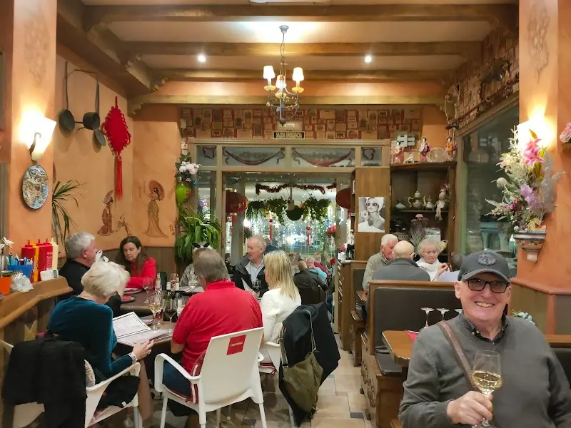 Indoor dining room with wooden beams, a chandelier and Chinese decorations, full of customers