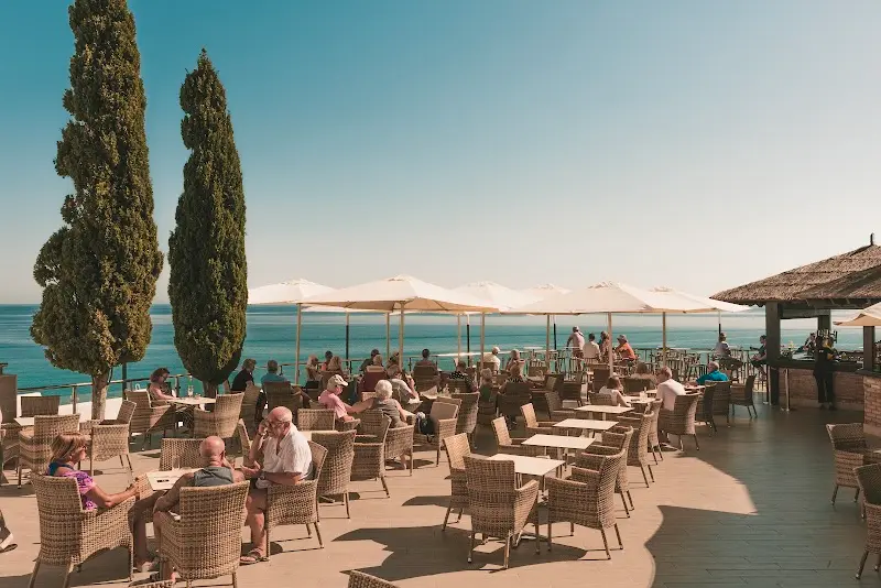 Cochran's terrace with wicker chairs, cypress trees and views of the Mediterranean