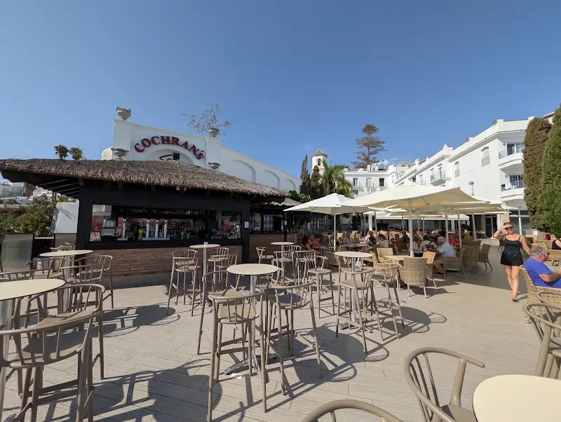 Thatched-roof bar and stools beneath the Cochran's sign on a sunny day