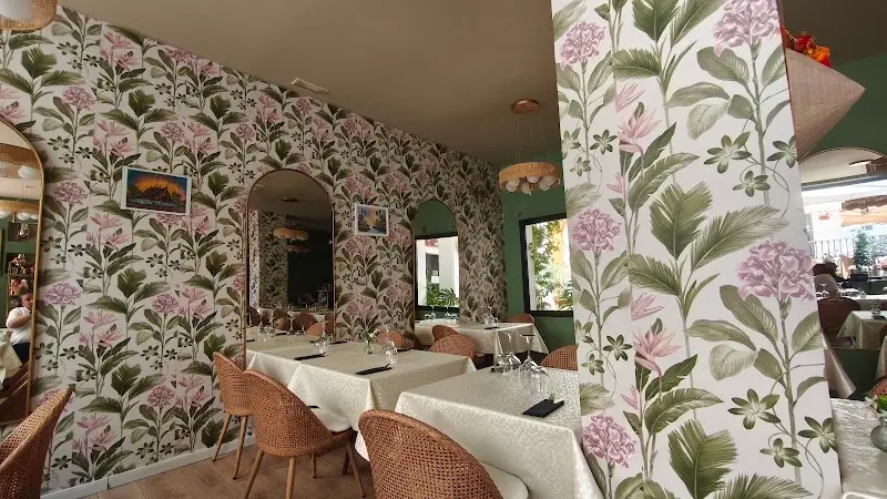 Dining area with floral and leaf wallpaper, arched mirrors and white-clothed tables
