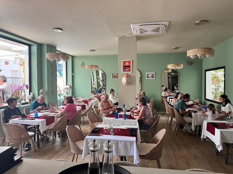 Dining room at Khao Hom with mint-green walls, woven lamps and tables laid in red and white