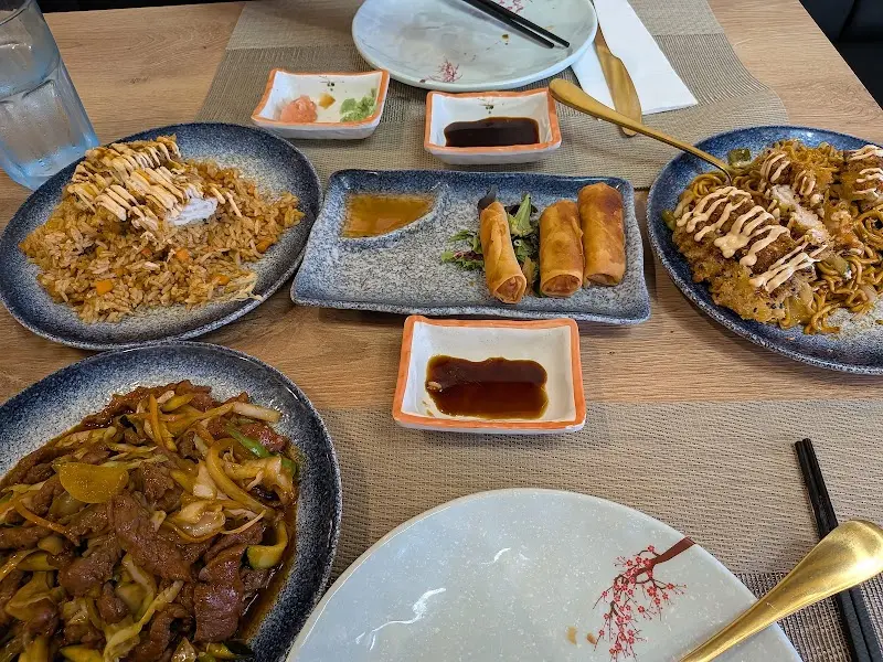 Table with fried rice, stir-fried noodles, spring rolls and beef with vegetables