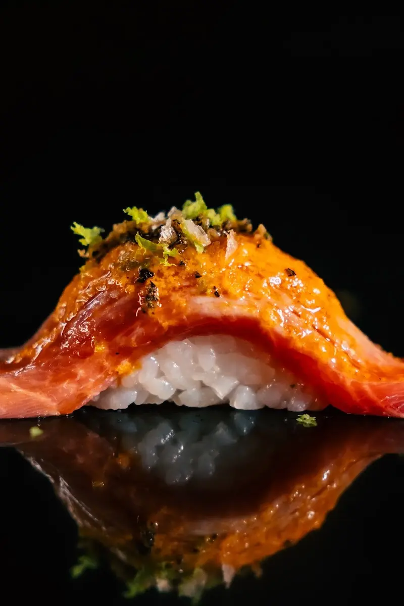 Seared red fish nigiri with an orange sauce and lime zest