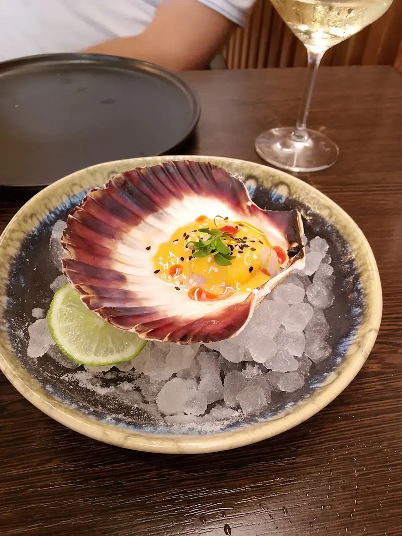 Scallop served in its shell on crushed ice with lime at Origen Nerja