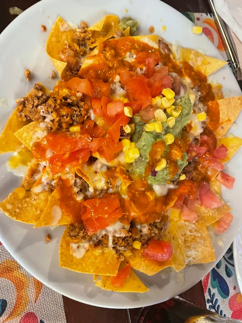 Nachos with minced meat, melted cheese, guacamole, tomato and sweetcorn