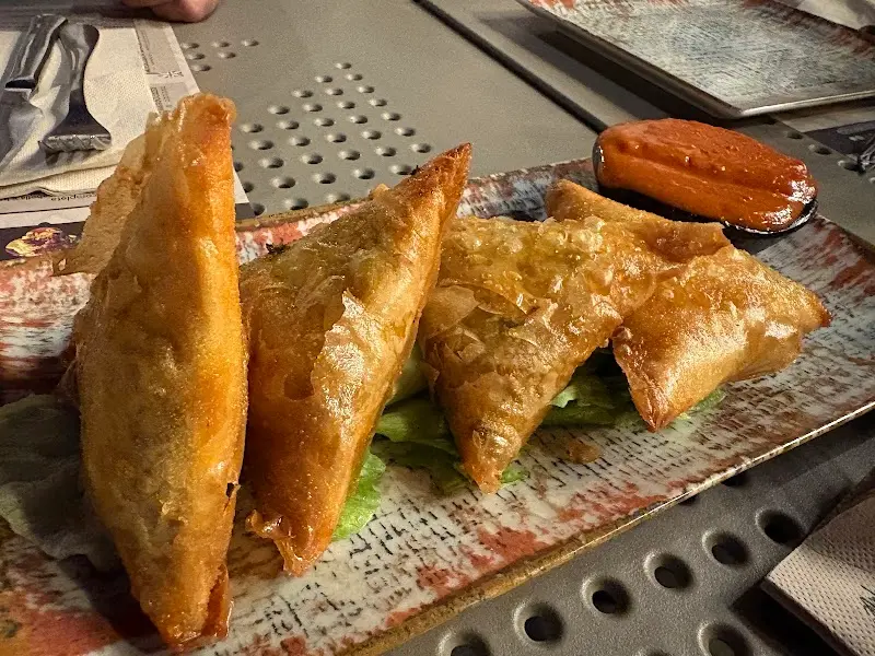 Fried filo pastry briouats on lettuce, with a red dipping sauce