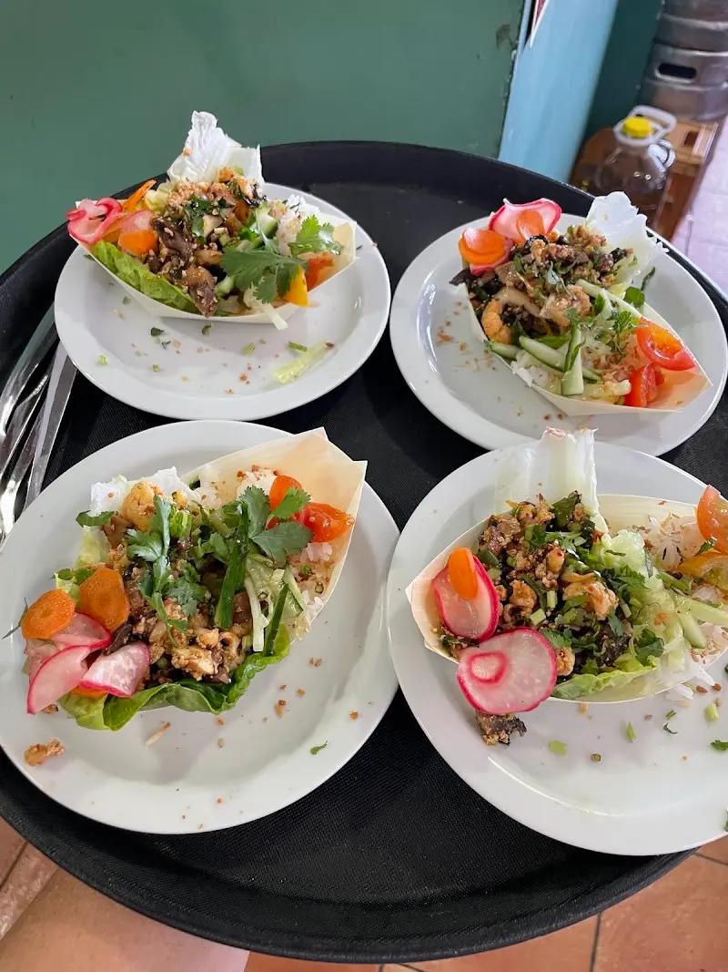 Four plates of lettuce wraps with minced meat, radish, carrot and coriander on a tray