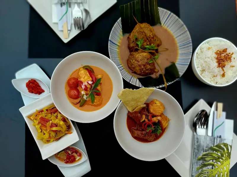 Overhead view of a table with Thai curries, white rice and small side dishes