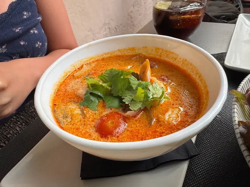 Bowl of spicy soup with prawns, cherry tomato and fresh coriander at SomSom