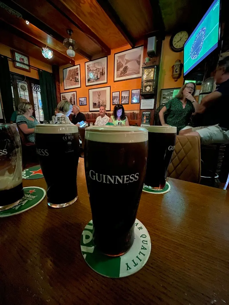 Pints of Guinness on the bar with customers and picture-lined walls behind