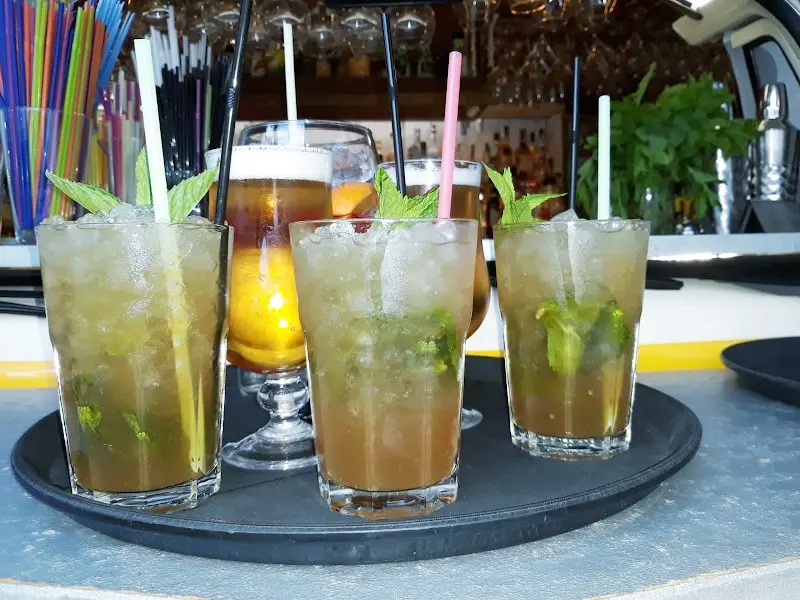 Mojitos with fresh mint and cocktails on a tray at the bar