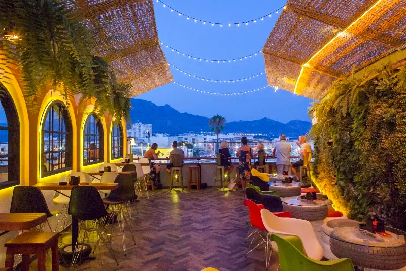 Volk's Bar Sevillano's rooftop terrace at dusk, with string lights and views of the mountains